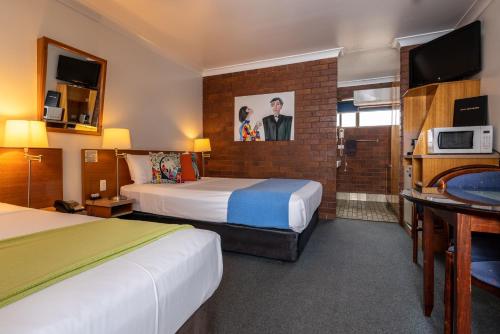 a hotel room with two beds and a bathroom at Country Pathfinder Motor Inn in Dalby