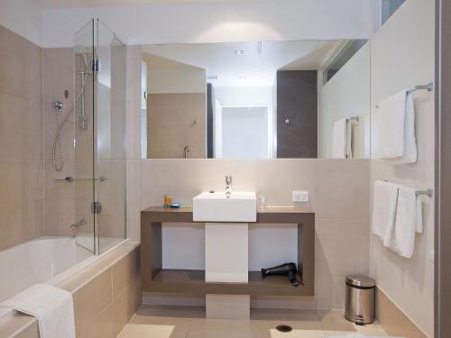 a bathroom with a sink and a bath tub and a mirror at Resort Apartment 109 in Torquay