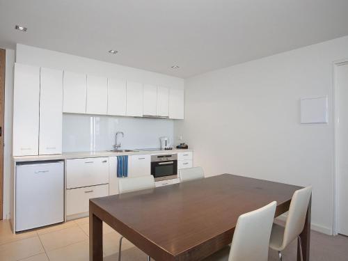 a kitchen with a wooden table and white cabinets at Resort Apartment 109 in Torquay
