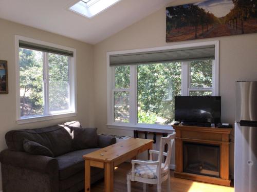 a living room with a couch and a table and windows at Amitabha Wine Country Cottage in Santa Rosa