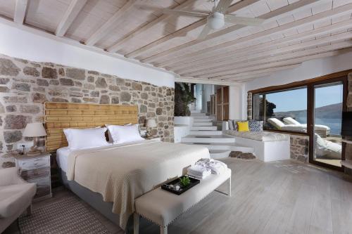 1 dormitorio con cama y pared de piedra en Albatros Club Mykonos, en Panormos  Mykonos