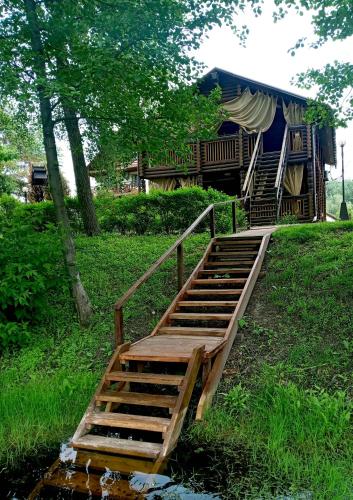 a wooden stairs leading to a house with a gazebo at Котедж-парк Славна in Okhtyrka