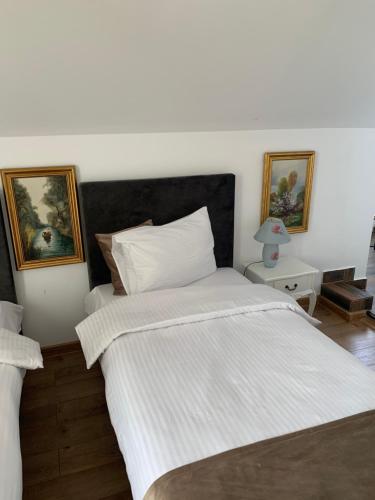 a bedroom with a large bed with white sheets at Casa Boem in Mogoşoaia