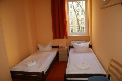 two beds in a room with a window at Happy Go Lucky Hotel + Hostel in Berlin