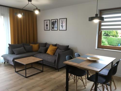 uma sala de estar com um sofá e uma mesa em Apartamenty Black&White Lubawka - Domek z ruską banią i sauną em Lubawka