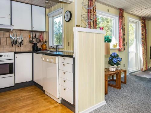 6 person holiday home in R m في Kongsmark: مطبخ مع دواليب بيضاء وساعة على الحائط