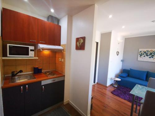 a kitchen with a sink and a blue couch at Airport Garden Apartments in Čilipi