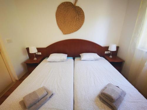 a bedroom with two beds with white sheets and two lamps at Airport Garden Apartments in Čilipi