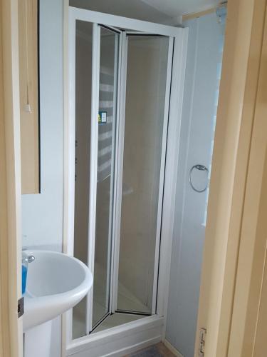 uma casa de banho com um chuveiro e um lavatório branco em Pine Ridge 59 Rockley Park Poole with sea view sleeps six em Poole
