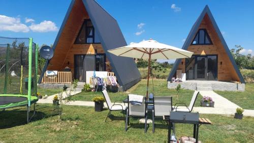 ein Haus mit einem Regenschirm und Stühlen davor in der Unterkunft olive garden farm in Ulcinj