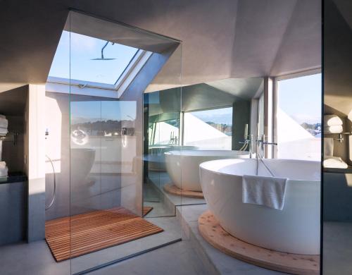 a bathroom with two tubs and a glass wall at Villa Cascais Boutique Hotel in Cascais