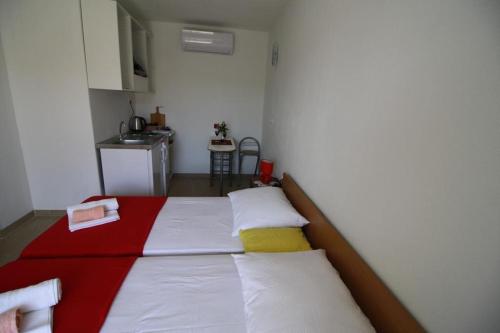 Bett mit roten weißen und gelben Kissen in einem Zimmer in der Unterkunft Apartment Gita in Sumartin
