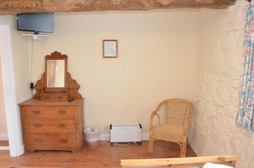 a room with a dresser and a mirror and a chair at The Royal Oak Inn in Dunsford