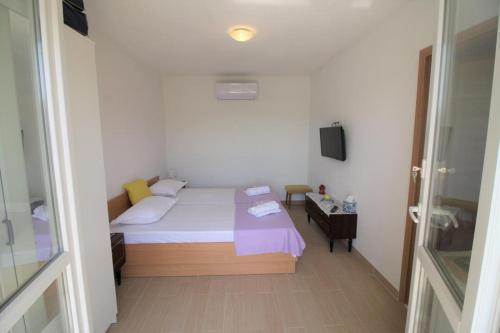 a small bedroom with a bed and a television at Privatna Soba Gita in Sumartin
