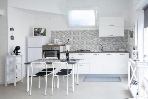 a kitchen with white cabinets and a table and chairs at Home & Bike Capelli di Venere in Casaletto Spartano