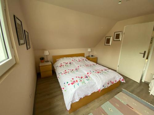 a bedroom with a bed with a white blanket with red flowers at Gästehaus VillaVerde in Kelberg