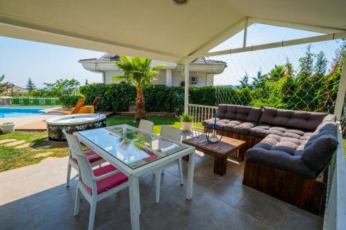 a patio with a table and a couch and a table and chairs at Milez Sultan luxury villa by Solo Villa in Oludeniz