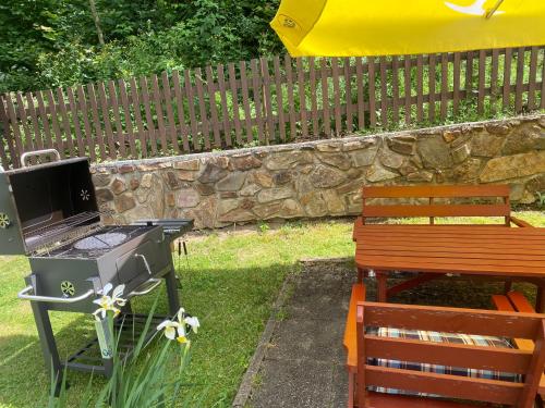 a grill and a bench in a yard next to a fence at Penzion U Rodinky in Bělá pod Pradědem