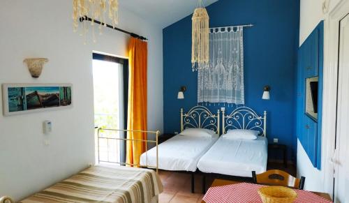 two beds in a room with blue walls and a window at Lontos Village in Finikounta