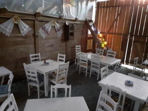 a dining room with white tables and white chairs at Pensiunea Energy in Căpuşu Mic