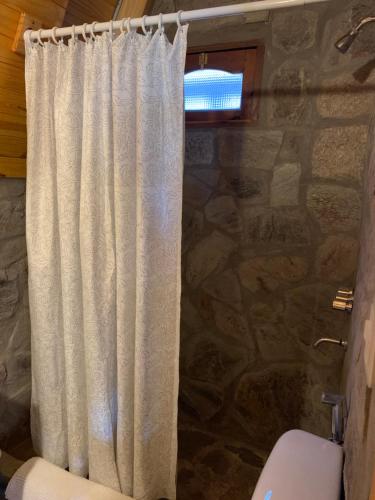 een douchegordijn in een badkamer met een stenen muur bij Cabañas El Mirador in El Volcán