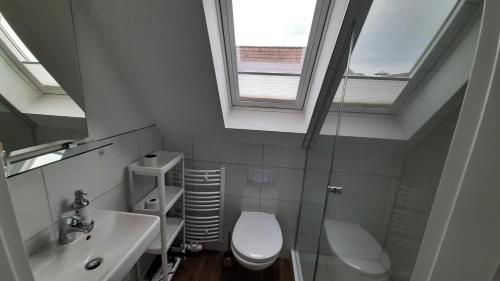 a bathroom with a toilet and a sink and a window at Haus am Hafen in Leer