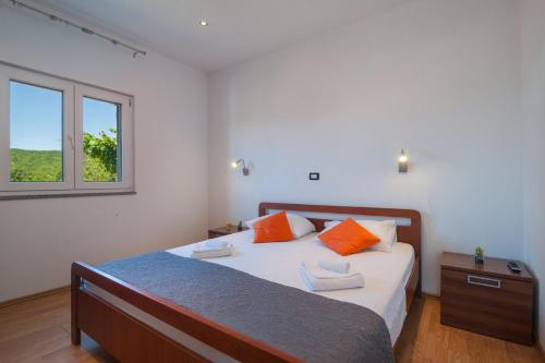 a bedroom with a bed with orange pillows and a window at Holiday Home Mateovi Dvori in Imotski