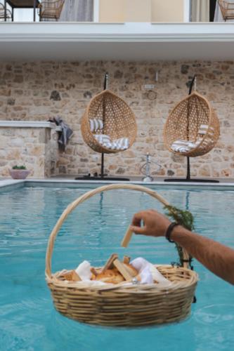a person holding a basket in a swimming pool at Liberte Maisonettes in Parga