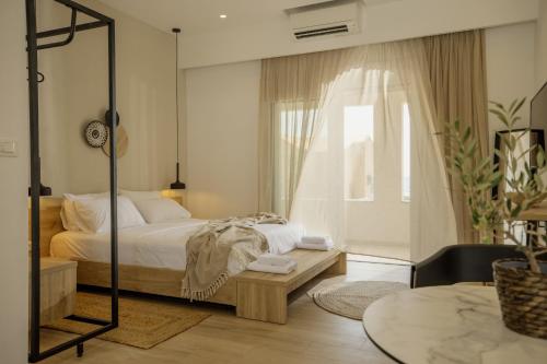 a bedroom with a bed and a table and a window at Casa Costa Suites in Kanali