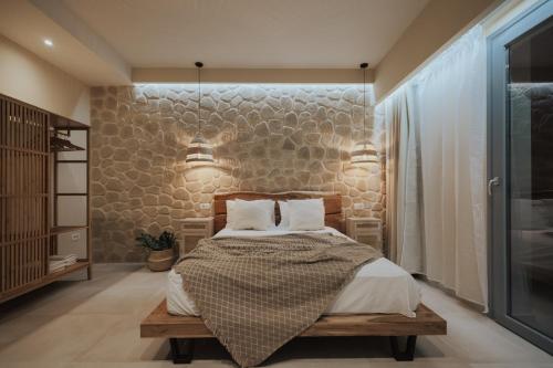 a bedroom with a bed and a stone wall at Liberte Maisonettes in Parga