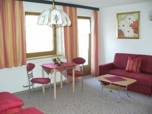 a living room with a red couch and a table at Ferienwohnungen Egger in Zell am Ziller