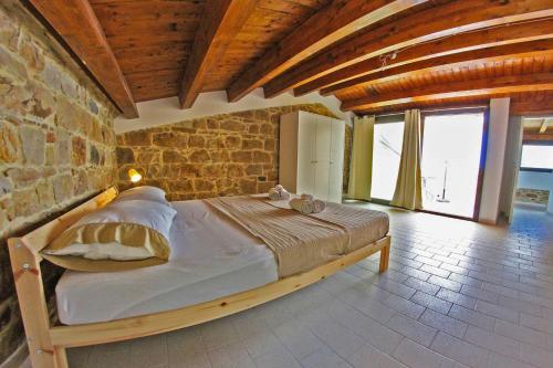 1 dormitorio con 1 cama grande en una pared de ladrillo en Il Miglio in Più, en Castel di Tusa