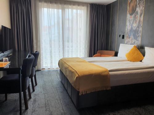 a hotel room with a bed and a desk and a window at Vila Topaz in Baile Felix