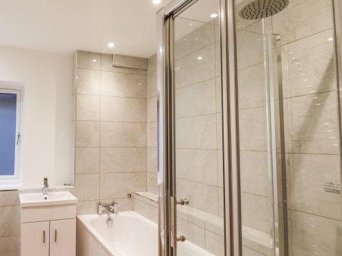 a bathroom with a shower and a tub and a sink at Exning Residence in Newmarket