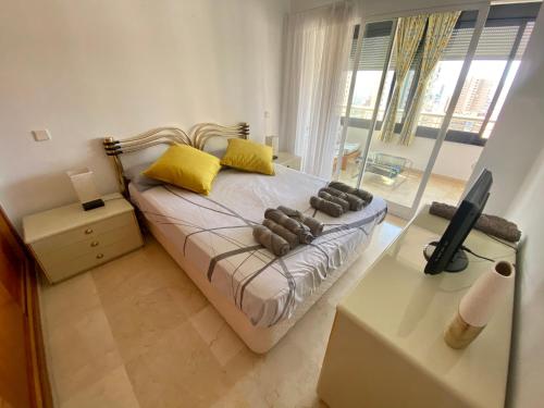 Un dormitorio con una cama con almohadas amarillas y una ventana en Apartamento COFFEE BEACH en PARQUE EUROPA, en Benidorm