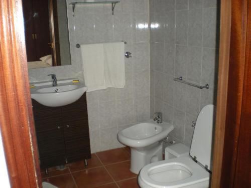 ein Badezimmer mit weißer Toilette und Waschbecken in der Unterkunft O ROCHA in Paredes do Rio