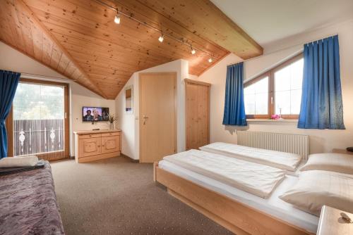 a bedroom with a large bed and blue curtains at Gästehaus Gratz - inklusive Eintritt in die Alpentherme in Dorfgastein
