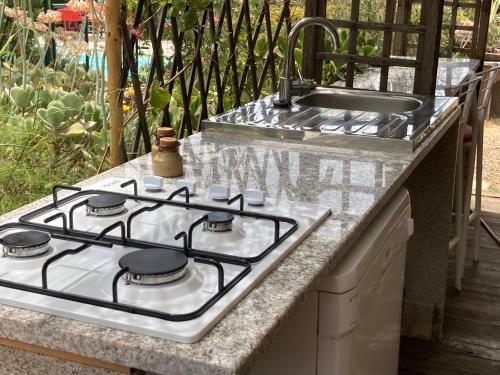 a stove top oven sitting next to a sink at B&B Macchia Verdata avec piscine in Monacia-dʼAullène