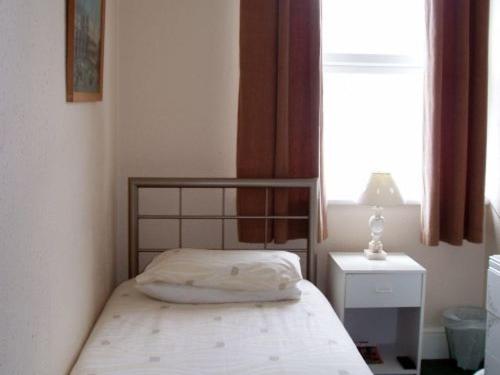 a small bedroom with a bed and a window at Breken Guest House in Exmouth