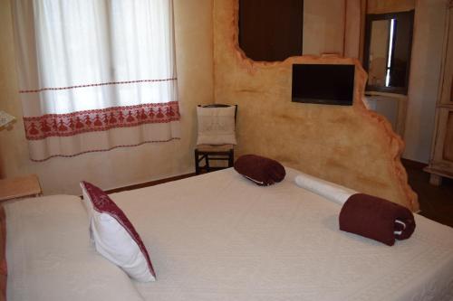a bedroom with a bed and a tv on the wall at Canne al Vento in Galtellì