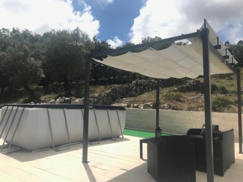 a pavilion with a table and a white umbrella at Recanto da Serra in Porto de Mós