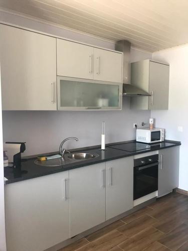 a kitchen with white cabinets and a sink and a microwave at Recanto da Serra in Porto de Mós