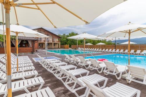 a group of white chairs and umbrellas next to a swimming pool at Sofion hotel&resort in Solotvyno