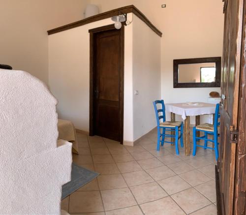 a dining room with a table and blue chairs at Canne al Vento in Galtellì