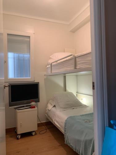 ein Schlafzimmer mit einem Etagenbett und einem TV in der Unterkunft Apartamento Canaleta Aitana frente al mar in Punta Umbría