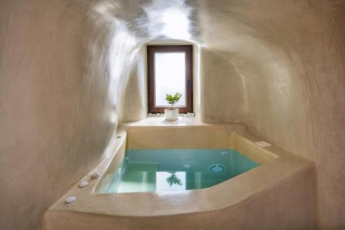 a bathroom with a bath tub with a window at Aegean Mist Luxury Suites in Megalochori