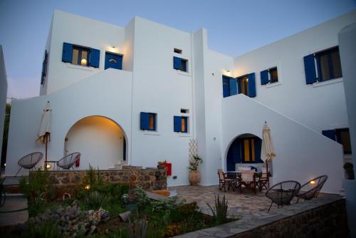 a large white building with a courtyard with tables and chairs at Kanellis Studios in Avlemonas