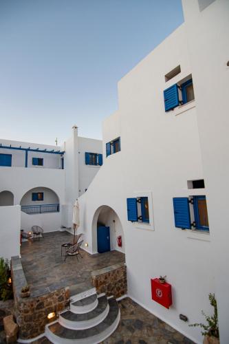 a large white building with blue windows and a patio at Kanellis Studios in Avlemonas