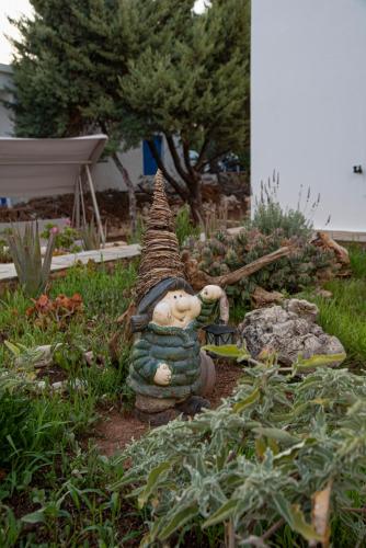 a gnome sitting in a garden with a building at Kanellis Studios in Avlemonas