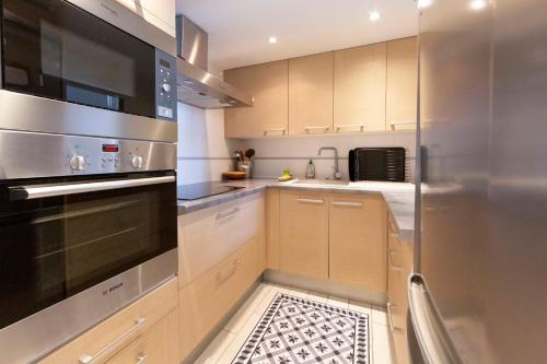 une cuisine avec des placards en bois et un appareil en acier inoxydable dans l'établissement 1 bedroom apartment with 1 mezzanine top location in the heart of Cannes, à Cannes